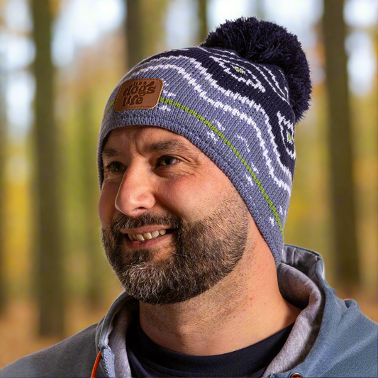 Man wearing a patterned beanie with a logo in a forest setting